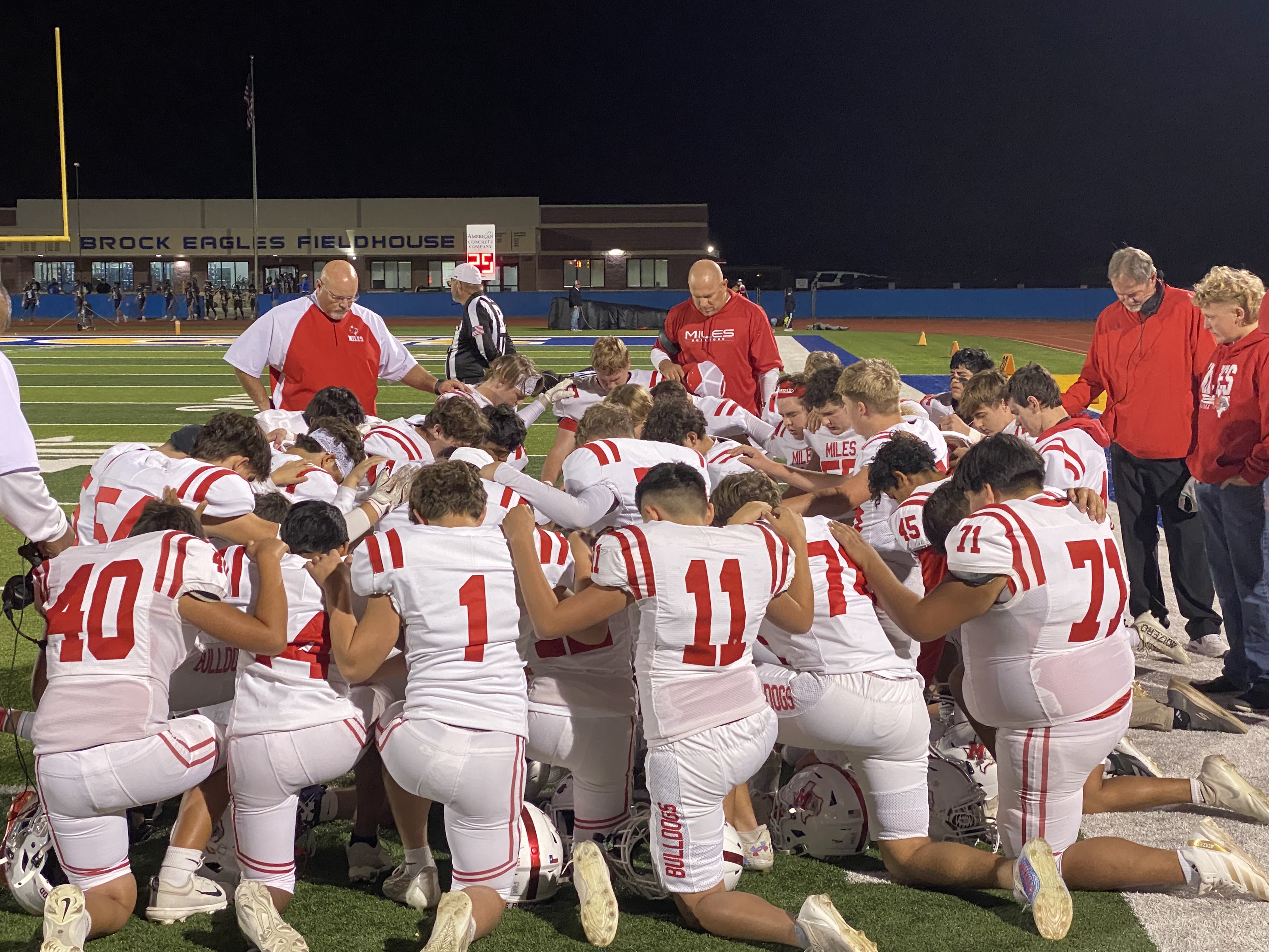 The Miles Bulldogs football team prays before its first-round playoff game against Lindsay in Brock on Thursday, Nov. 14, 2024.