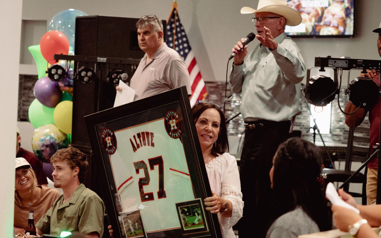 Joe Hyde, auctioneer Mike Smith, and Trish Smith manage the auctioning of a signed Houston Astros jersey donated by singer/songwriter Sterling Elza.