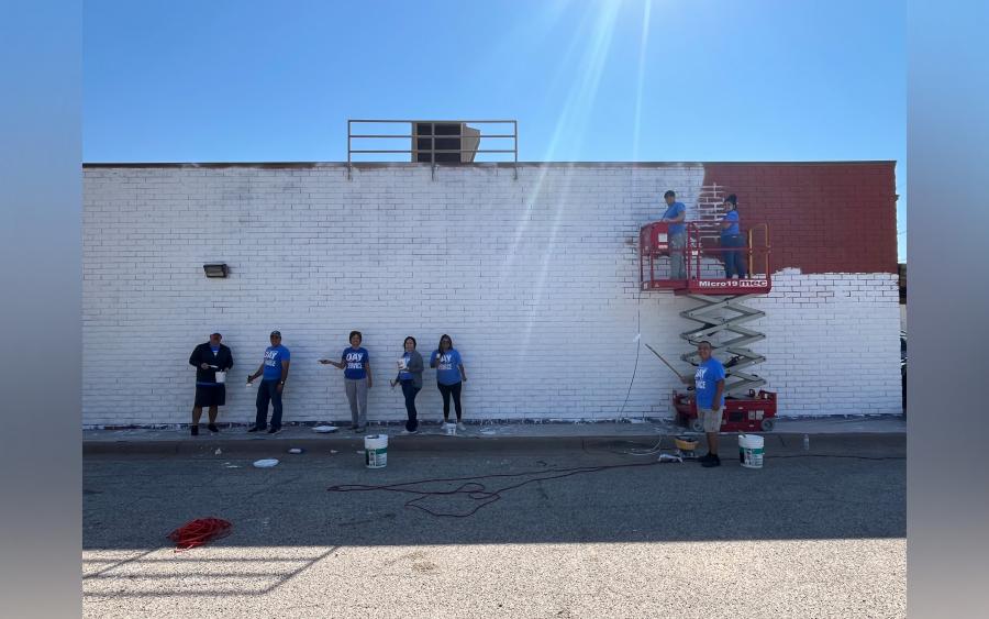 Volunteers from First Financial Bank paint an exterior wall at the United Way of the Concho Valley, preparing the site for a Centennial Mural.
