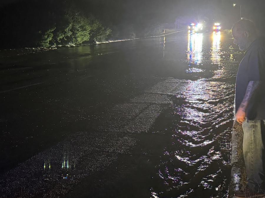 The rescued driver surveys the floodwaters where his car was swept off the road in San Angelo.