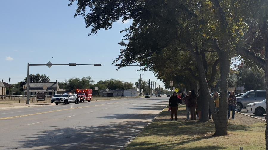 Bystanders stand across the street while a San Angelo Fire Department vehicle remains on standby during the investigation of a reported structure fire.