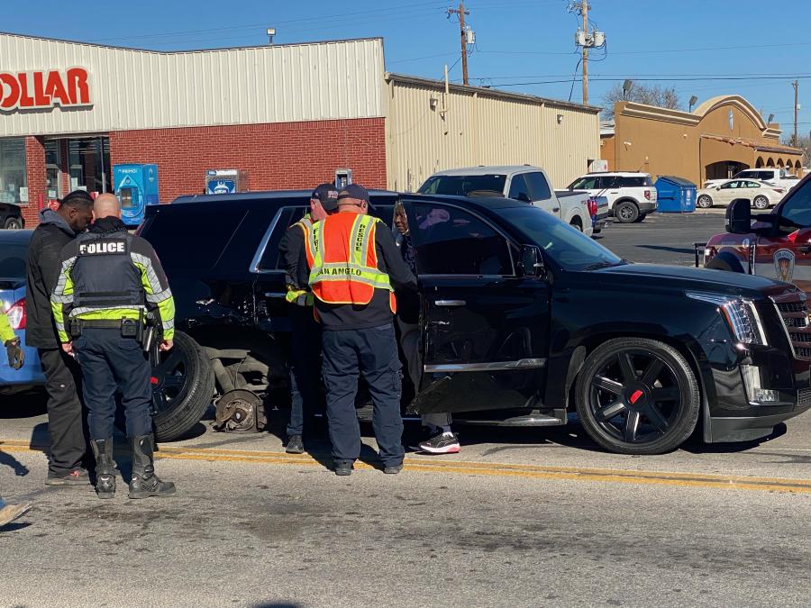 San Angelo police officers inspect the black Cadillac Escalade involved in the collision. The vehicle sustained significant damage to its side.