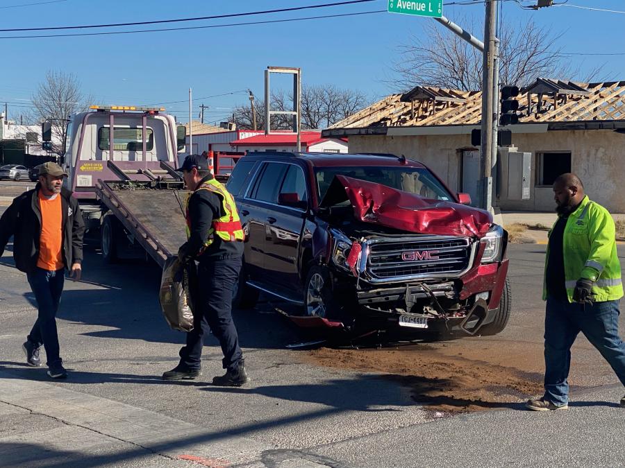 A maroon GMC Yukon is towed away from the intersection after sustaining heavy front-end damage in the crash.