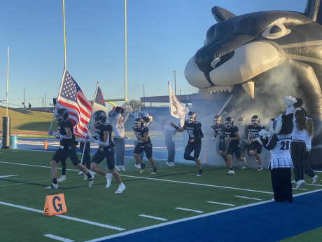 Water Valley's Branson Lacy (6) helps lead the Wildcats onto the field while carrying a flag.