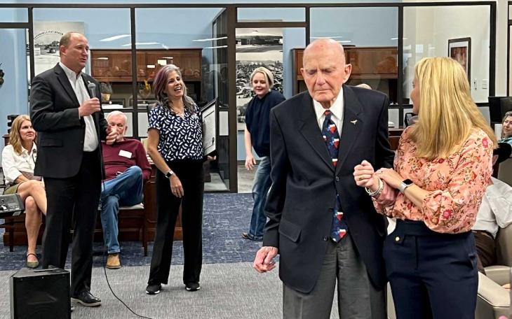 Texas Bank President Casey Barrett (left with mic) emcees the bank's 60th Anniversary party where John Mark McLaughlin was recognized. Mr. McLaughlin is standing with his granddaughter, Claire McLaughlin, who is an attorney in Midland.