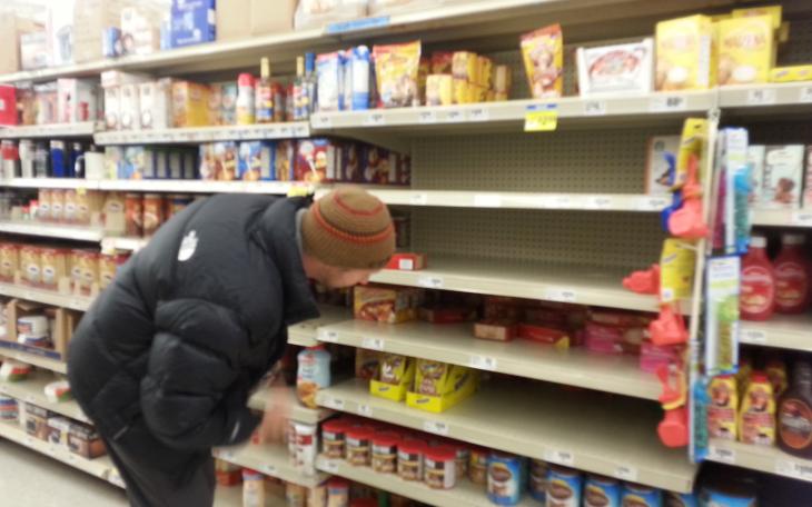A man in search of a box of cocoa peers to the back of an empty shelf at H-E-B. (LIVE! Photo by Chelsea Schmid)