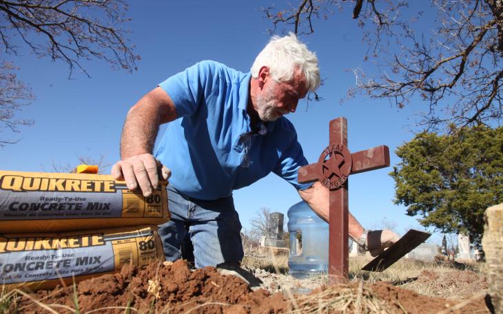 Garland Richards plants a Texas Rangers cross on the grave of Ranger Ben Warren. (Contributed Photo/David Carter)