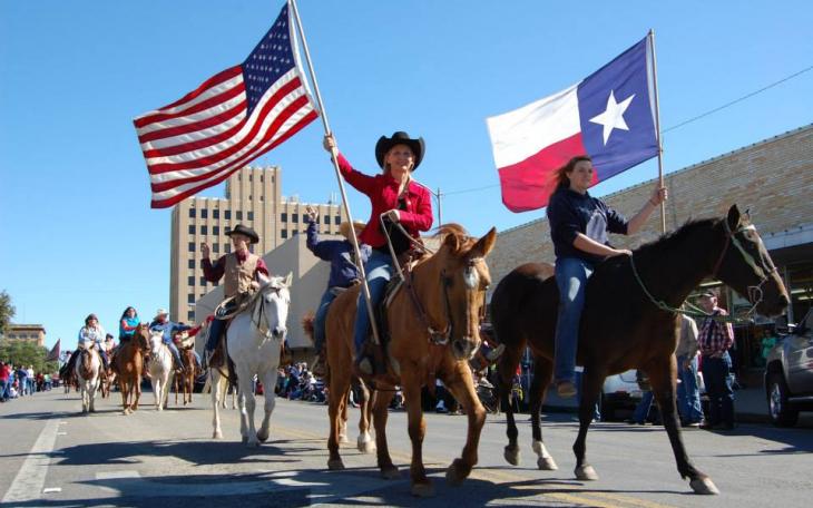 Two riders carrying the Texas and American flags bring in the Veterans Day Parade. (LIVE! Photo by Chelsea Schmid)